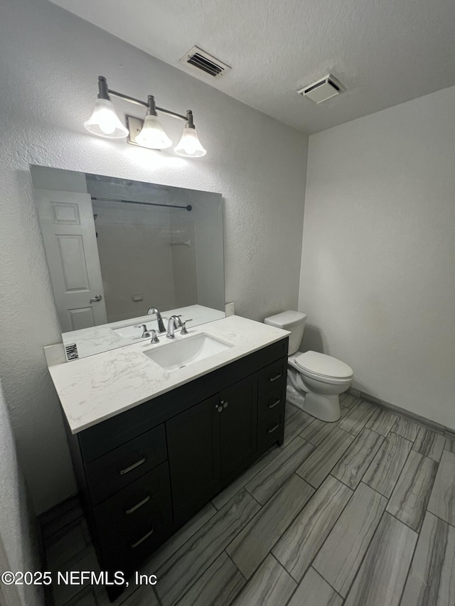 full bathroom featuring vanity, visible vents, a textured ceiling, and toilet