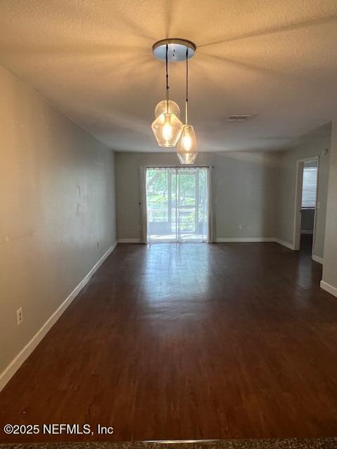 unfurnished room featuring dark wood-style flooring, baseboards, and a textured ceiling