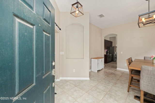 foyer featuring an inviting chandelier, a barn door, arched walkways, light tile patterned floors, and visible vents