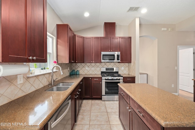 kitchen featuring stainless steel appliances, visible vents, a sink, and reddish brown cabinets