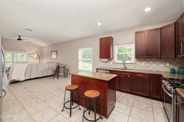 kitchen with decorative backsplash, a kitchen island, open floor plan, a sink, and appliances with stainless steel finishes
