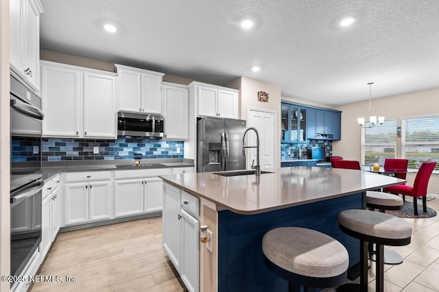 kitchen with an inviting chandelier, a kitchen breakfast bar, appliances with stainless steel finishes, and white cabinetry