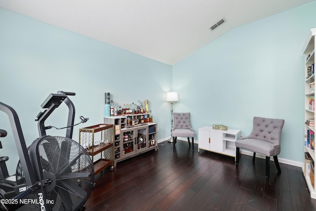 living area featuring lofted ceiling, baseboards, and wood finished floors