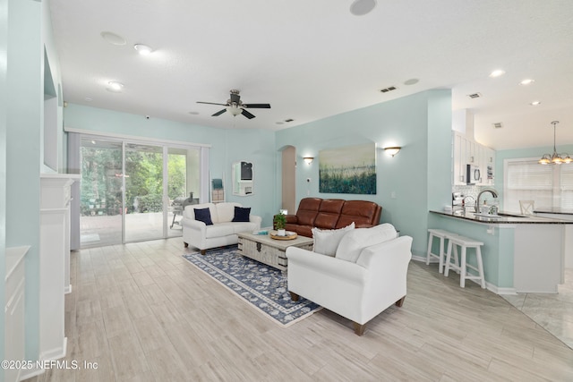 living area with ceiling fan, light wood finished floors, arched walkways, recessed lighting, and baseboards
