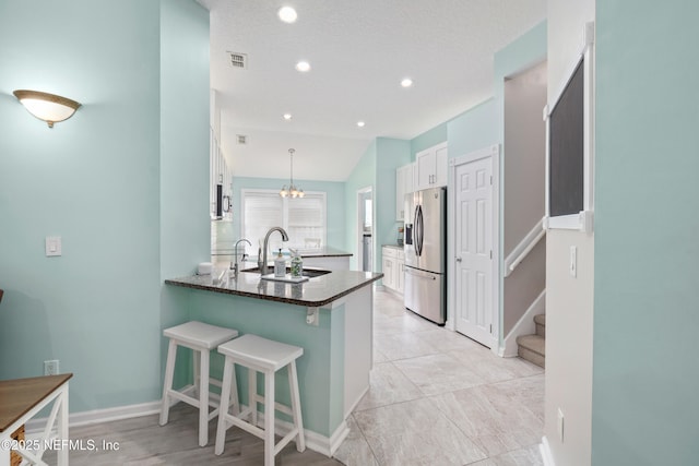 kitchen with stainless steel appliances, a sink, white cabinets, a peninsula, and a kitchen bar