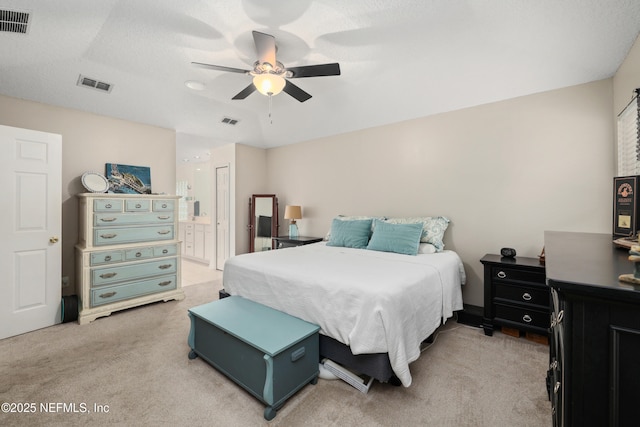 bedroom featuring light carpet, ensuite bath, and a ceiling fan