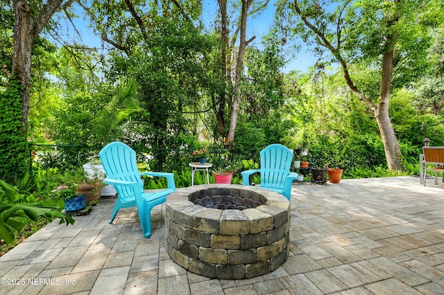 view of patio / terrace featuring an outdoor fire pit and view of wooded area