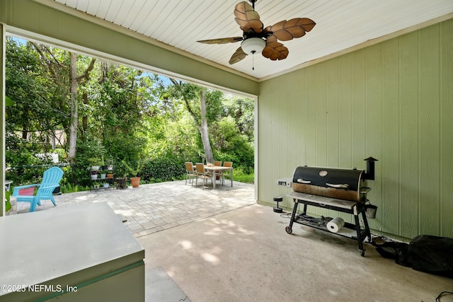 view of patio / terrace with outdoor dining area, a ceiling fan, view of scattered trees, and area for grilling