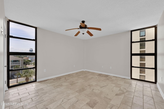 2200 Ocean Dr Unit 4A, Jacksonville Beach, FL 32050 - unfurnished room with a textured ceiling, a ceiling fan, baseboards, stone finish flooring, and expansive windows
