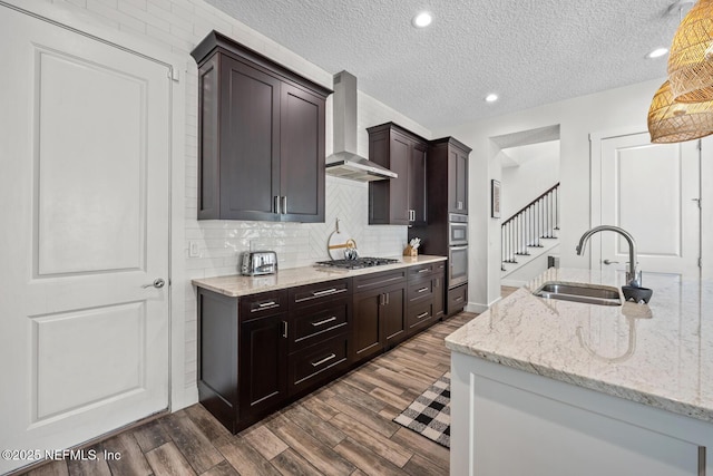 kitchen with a sink, wall chimney exhaust hood, tasteful backsplash, dark wood-style floors, and stainless steel appliances