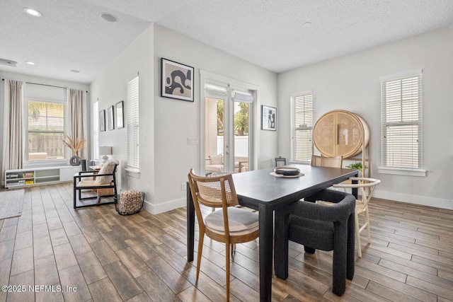 dining area with baseboards, wood finished floors, recessed lighting, and a textured ceiling