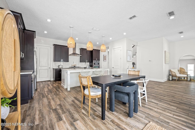 dining area with recessed lighting, a textured ceiling, visible vents, and wood finished floors
