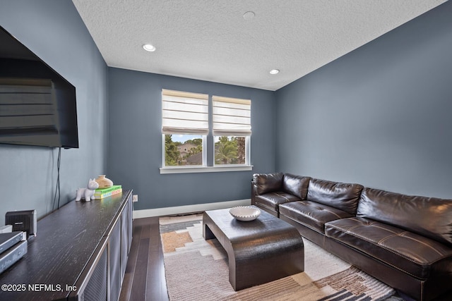 living area featuring recessed lighting, dark wood-type flooring, baseboards, and a textured ceiling
