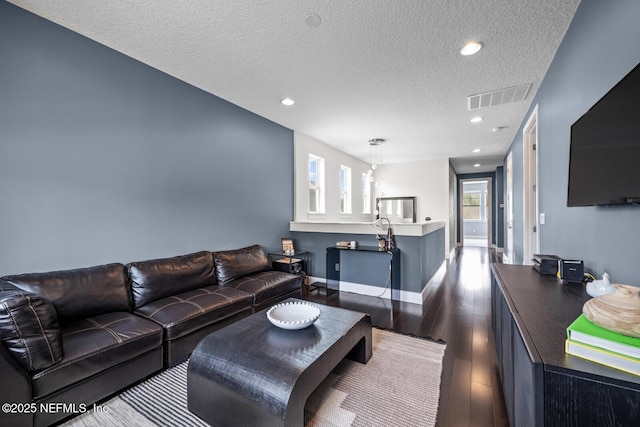 living area with a textured ceiling, visible vents, recessed lighting, and dark wood finished floors