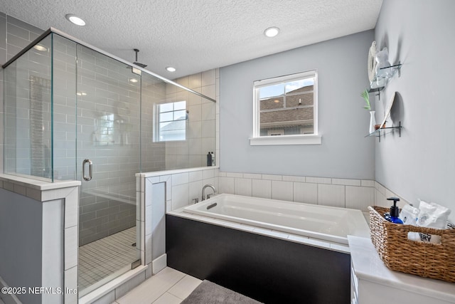 bathroom featuring a textured ceiling, a garden tub, recessed lighting, and a shower stall