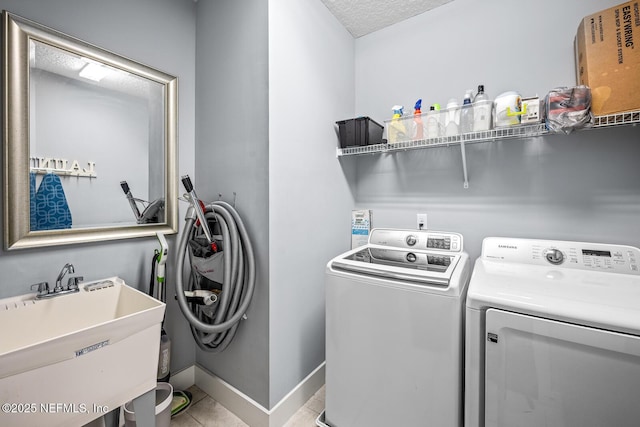 washroom featuring washer and clothes dryer, a sink, tile patterned flooring, laundry area, and baseboards
