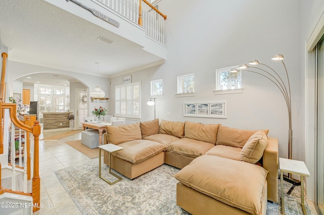 96064 Bottlebrush Ln, Fernandina Beach, FL 32034 - tiled living room with a healthy amount of sunlight, arched walkways, a towering ceiling, and ornamental molding