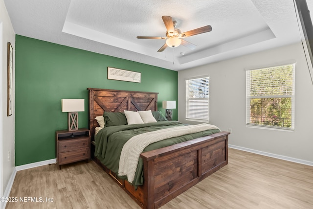 208 Seville Pkwy, Saint Augustine, FL 32086 - bedroom with a tray ceiling, baseboards, and light wood finished floors