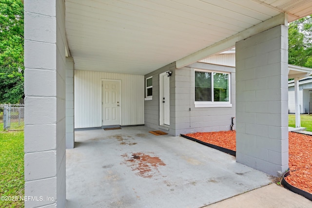entrance to property featuring fence, a carport, and concrete block siding
