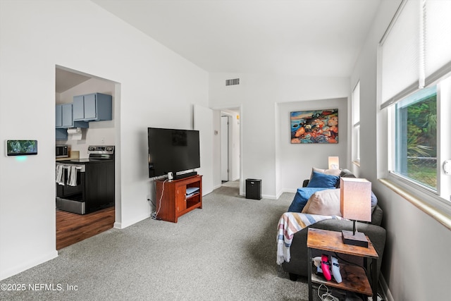 living area with lofted ceiling, visible vents, carpet, and baseboards