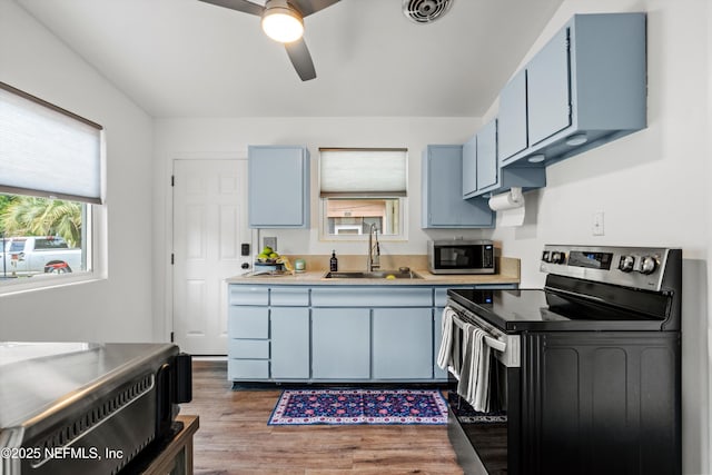 kitchen featuring a sink, blue cabinetry, a ceiling fan, visible vents, and appliances with stainless steel finishes