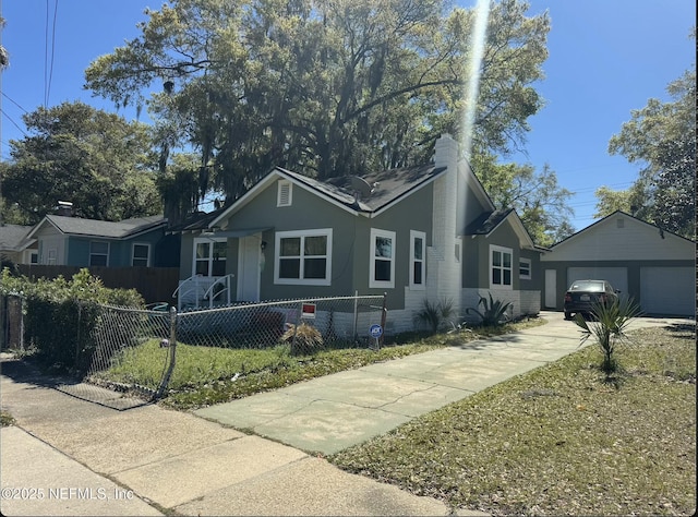single story home featuring a garage, an outbuilding, and a fenced front yard