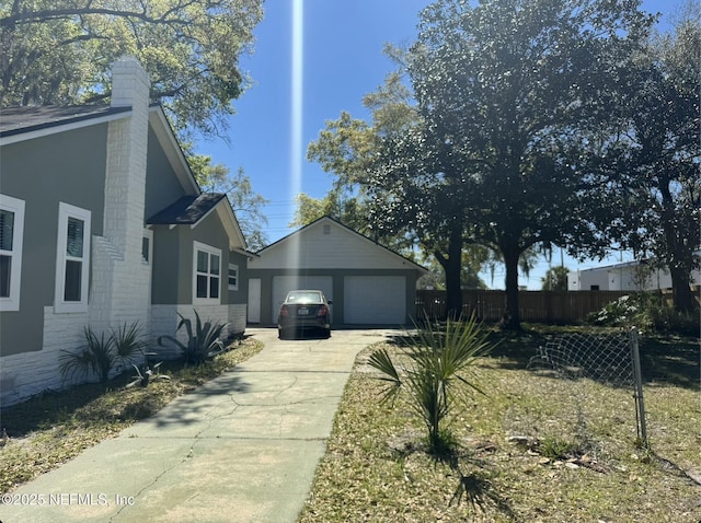 view of side of property featuring a garage, fence, an outdoor structure, and brick siding