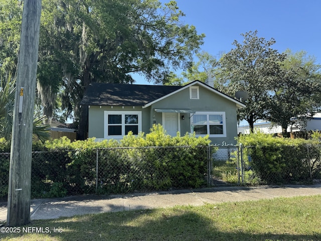 bungalow with a fenced front yard, stucco siding, and a gate
