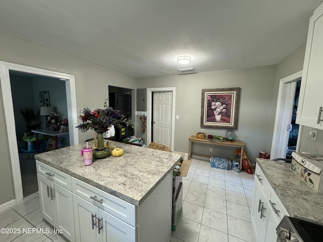 kitchen featuring white cabinets, range, marble finish floor, and a kitchen island