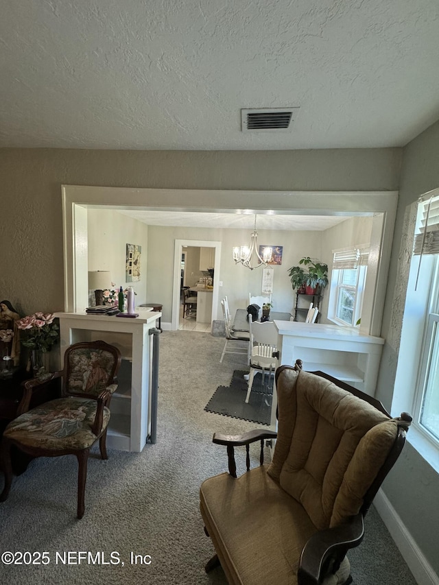 living room with visible vents, carpet flooring, a chandelier, and a textured ceiling