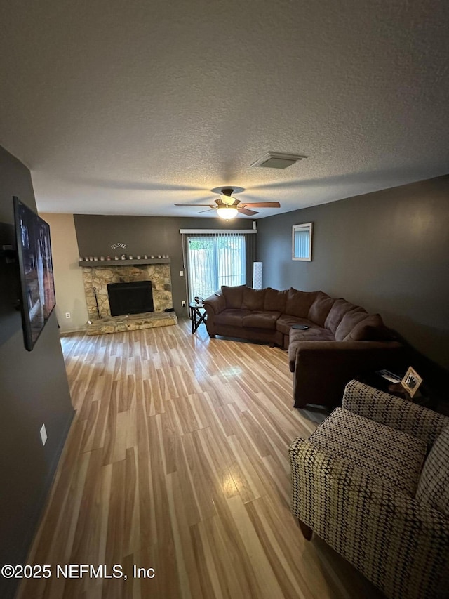11726 Tanager Dr, Jacksonville, FL 32225 - living room featuring visible vents, a ceiling fan, a textured ceiling, wood finished floors, and a fireplace