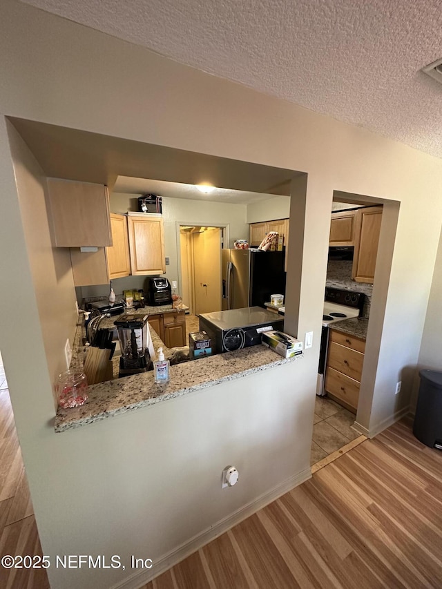 11726 Tanager Dr, Jacksonville, FL 32225 - kitchen with electric range, light wood-style flooring, light brown cabinets, a textured ceiling, and stainless steel fridge