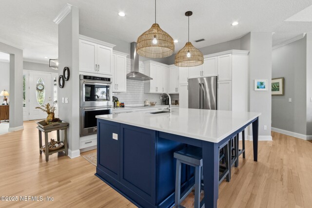 5698 Grand Cayman Rd, Jacksonville, FL 32226 - kitchen featuring white cabinetry, stainless steel appliances, wall chimney exhaust hood, and a sink