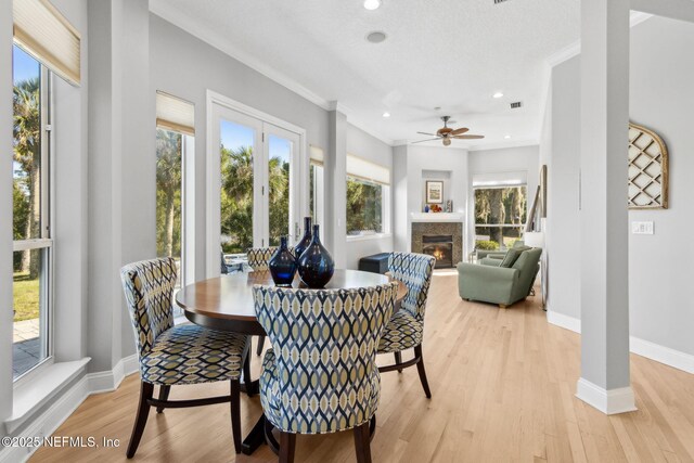 5698 Grand Cayman Rd, Jacksonville, FL 32226 - dining area featuring a glass covered fireplace, crown molding, baseboards, and light wood finished floors