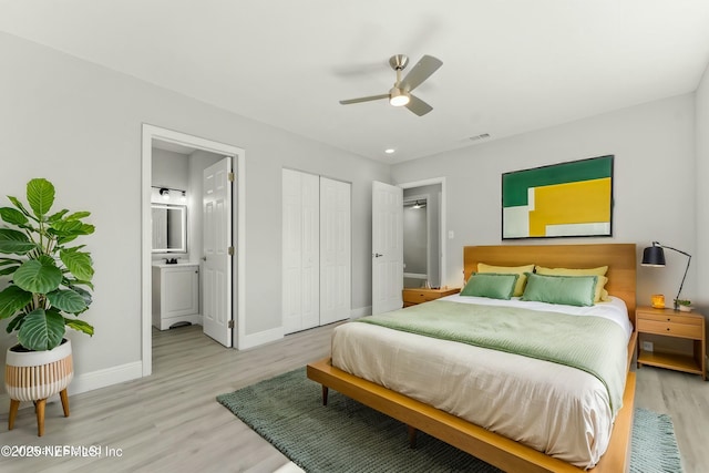 bedroom featuring visible vents, baseboards, ensuite bathroom, and light wood-style floors