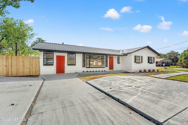 view of front of home featuring metal roof and fence
