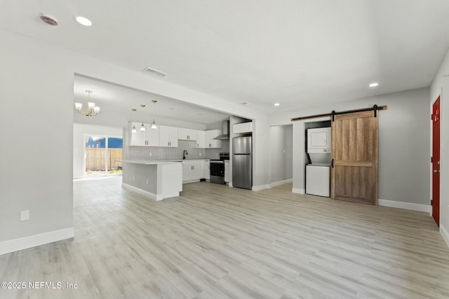 unfurnished living room with visible vents, a barn door, an inviting chandelier, light wood-style floors, and a sink