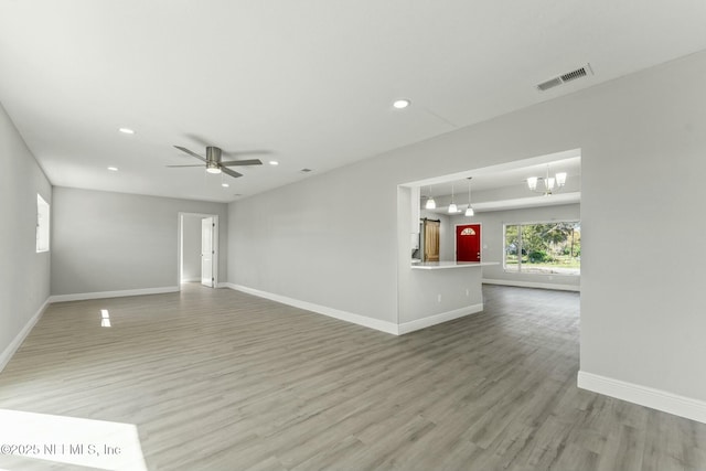 unfurnished living room with visible vents, light wood-style flooring, ceiling fan with notable chandelier, recessed lighting, and baseboards