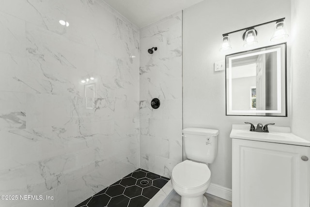 bathroom featuring baseboards, toilet, vanity, and a tile shower