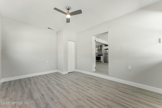 unfurnished room with visible vents, wood finished floors, baseboards, and ceiling fan