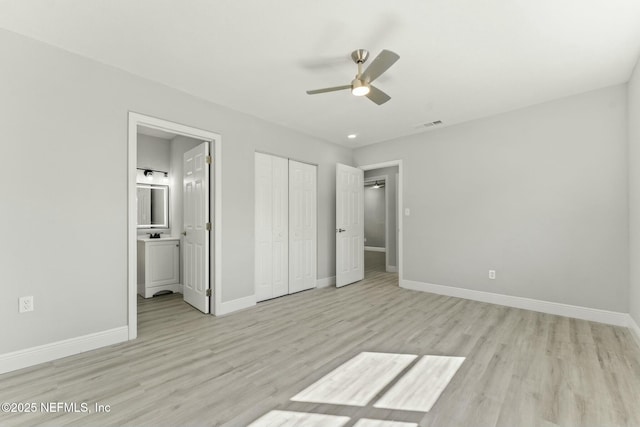 unfurnished bedroom with visible vents, baseboards, light wood-style flooring, ensuite bathroom, and a closet