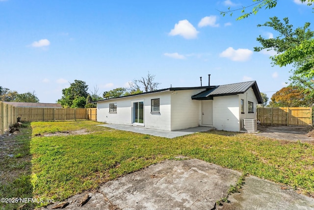 rear view of house featuring central air condition unit, a patio, a lawn, and a fenced backyard