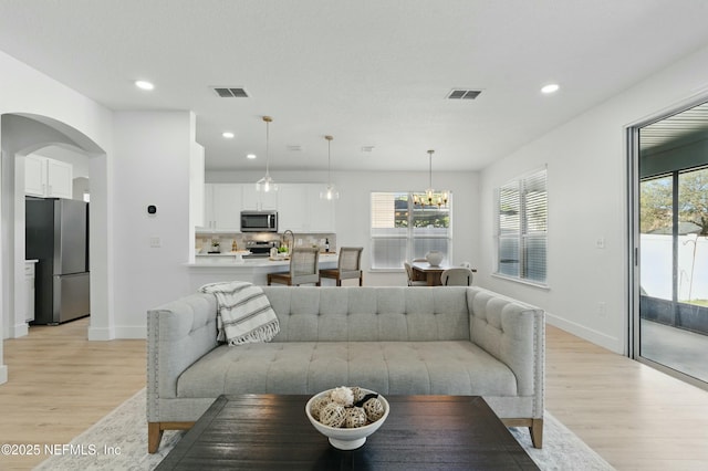 3852 Westridge Dr, Orange Park, FL 32065 - living area with light wood-style flooring, arched walkways, visible vents, and a wealth of natural light