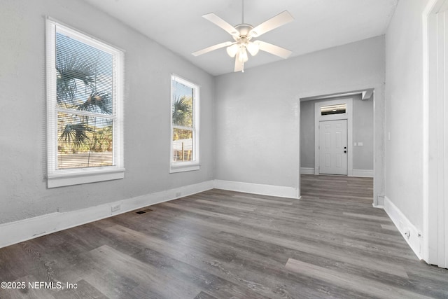 spare room featuring visible vents, baseboards, ceiling fan, and wood finished floors