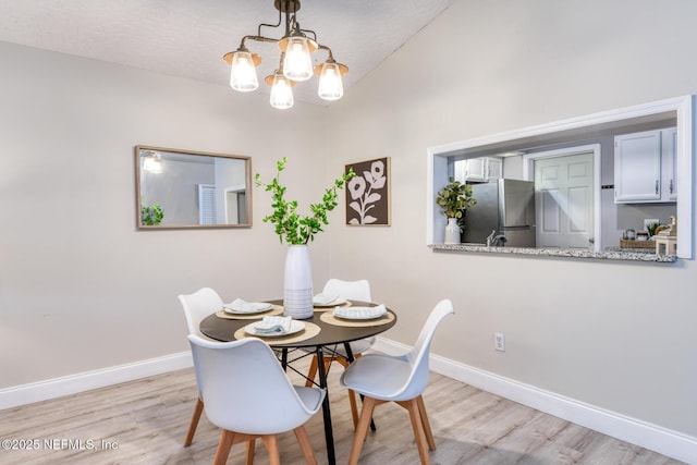 dining space with light wood-style flooring, baseboards, and a chandelier