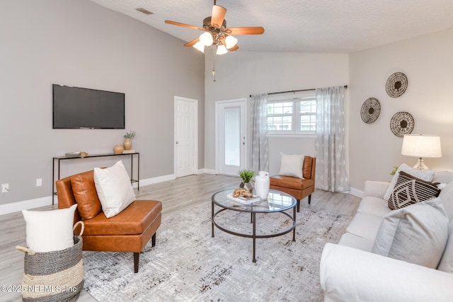 living area featuring baseboards, vaulted ceiling, wood finished floors, and ceiling fan