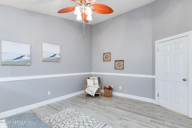 sitting room featuring baseboards, a ceiling fan, and wood finished floors