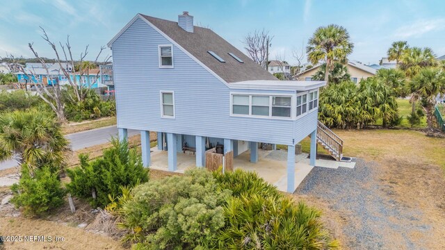 27 Flagler Dr, Palm Coast, FL 32137 - rear view of house featuring stairway, gravel driveway, roof with shingles, a carport, and a chimney