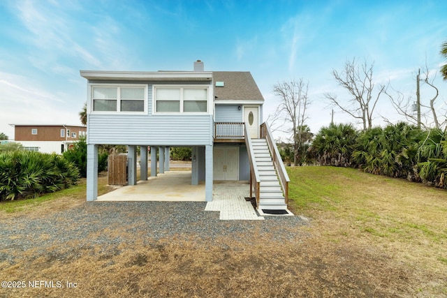 27 Flagler Dr, Palm Coast, FL 32137 - rear view of property featuring stairway, driveway, a yard, a chimney, and a carport