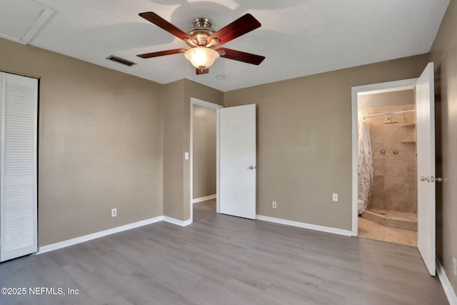 4245 New Hampshire Rd, Elkton, FL 32033 - unfurnished bedroom featuring baseboards, ensuite bath, visible vents, a ceiling fan, and wood finished floors